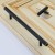 Czarny matowy uchwyt meblowy Poza zamontowany na jasnym drewnianym froncie szuflady 160 mm