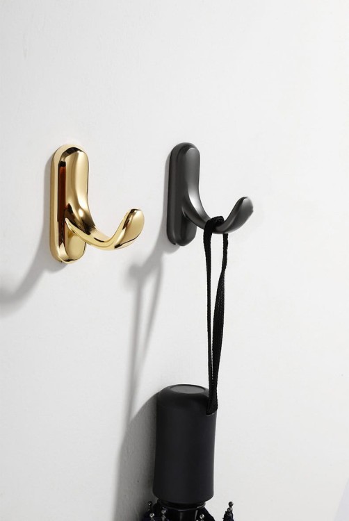 Wandhaken Bello – eleganter Haken mit geschwungener Form aus robustem Metall. Ideal für Flur, Bad und Garderobe. Farben: glänzendes Gold und Perlgrau. Montageschrauben im Set.
