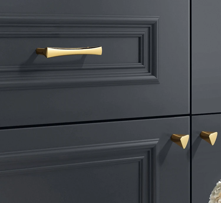 Elegancki złoty uchwyt do mebli Tuse zamontowany na czarnym froncie szuflady